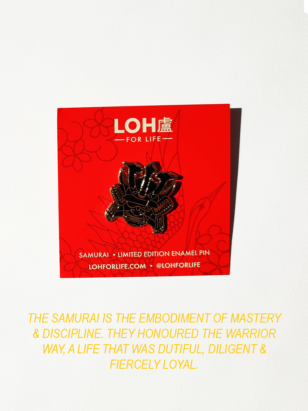 A red LOH For Life card displaying a black enamel samurai pin, with yellow text below on a white background.